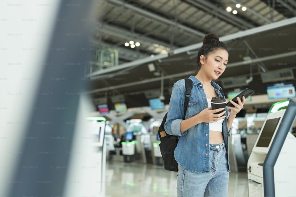Young woman using smartphone at airport self-service kiosk for Digi Yatra paperless entry